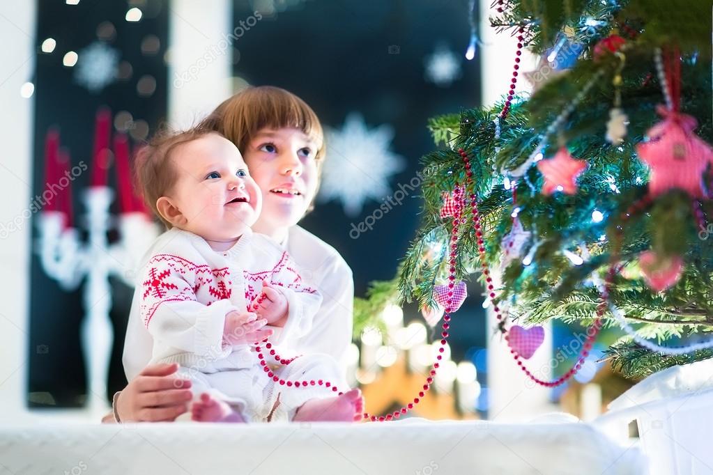 Brother and his baby sister at a Christmas tree