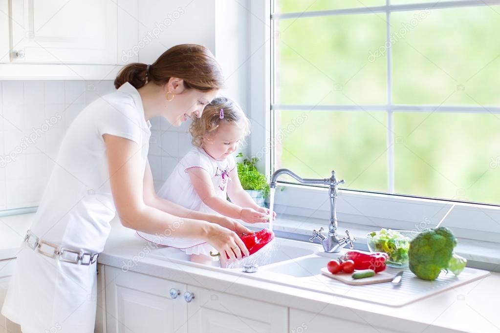 Mother and her daughter washing vegetables