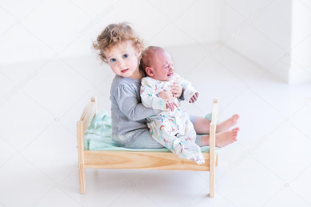 Toddler girl playing with her newborn baby brother