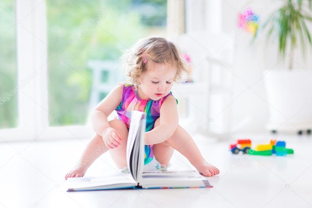 Girl with blond curly hair reading a book