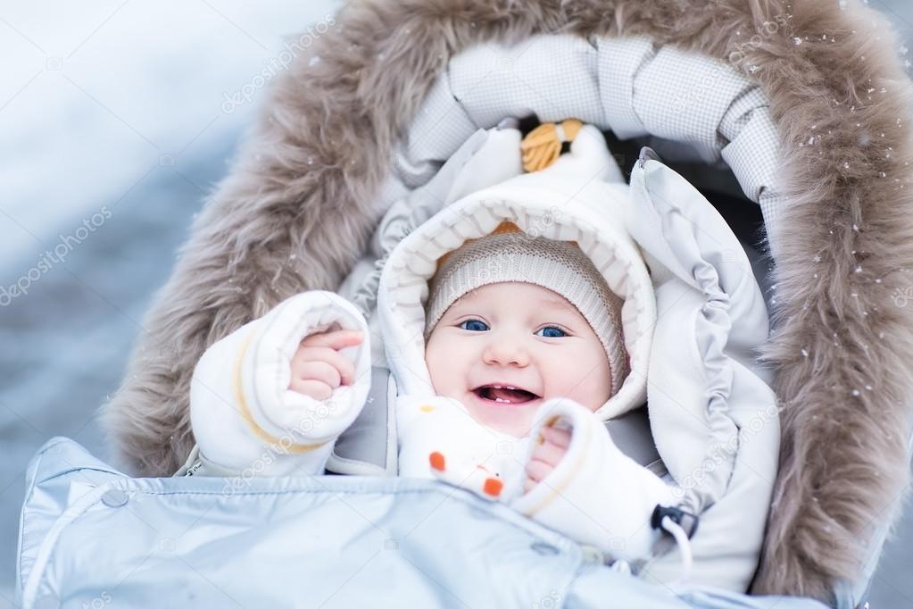 Baby girl enjoying a walk in a snowy winter park