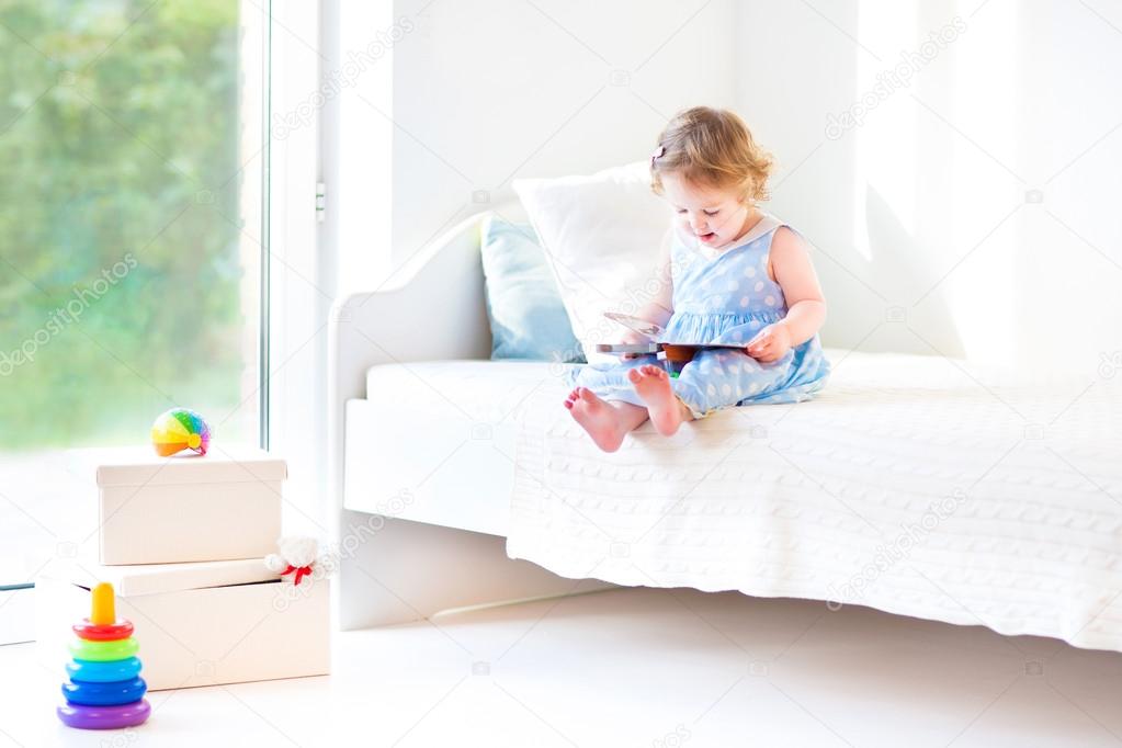 Toddler girl sitting on a white bed