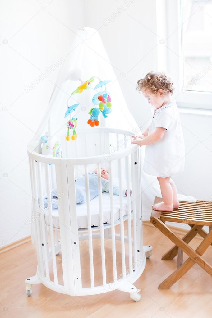 Toddler girl watching her newborn baby brother