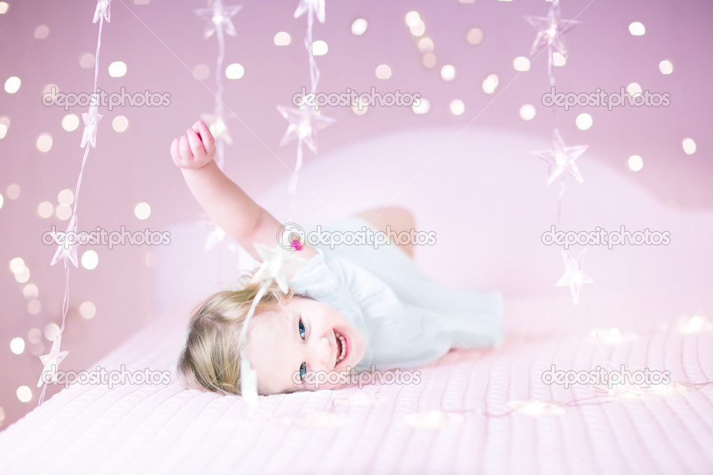 Toddler girl playing in a white bed