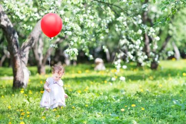 kırmızı bir balon ile oynayan kız bebek
