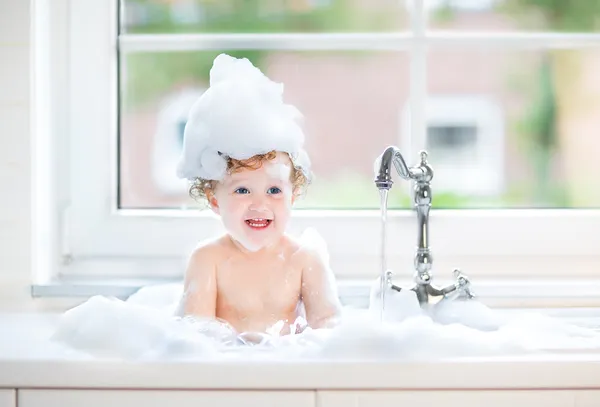 Baby girl with big blue eyes playing in a bath — Stock Photo, Image