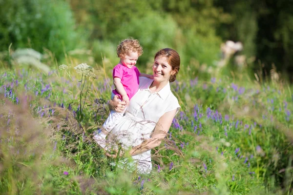 Mother holding her tired baby daughter in a park — Stock Photo, Image