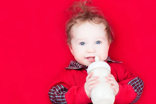Baby drinking milk on a red blanket — Stock Photo, Image