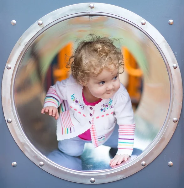 Baby flicka gömmer sig på en lekplats — Stockfoto