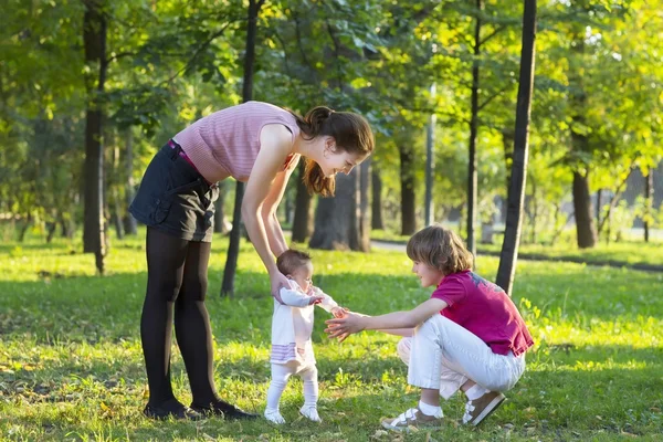 Mädchen macht erste Schritte mit Mutter und Bruder — Stockfoto