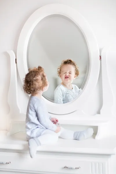 Niña mirando su reflejo en un espejo redondo — Foto de Stock