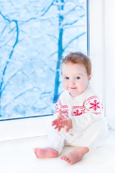 Beautiful baby girl sitting next to a window — Stock Photo, Image