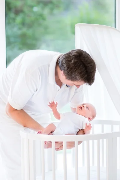 Junger lächelnder Vater legt sein neugeborenes Baby hin — Stockfoto