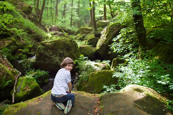 Мальчик играет у живописного водопада — стоковое фото