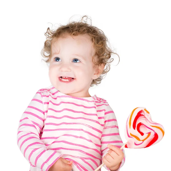 Niedliche lockige Mädchen mit einem herzförmigen Bonbons — Stockfoto