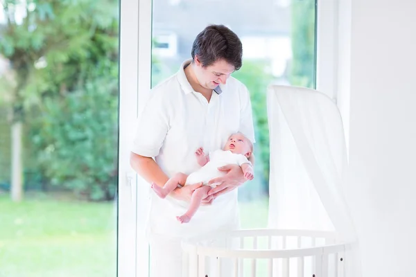 Junger lächelnder Vater legt sein neugeborenes Baby hin — Stockfoto