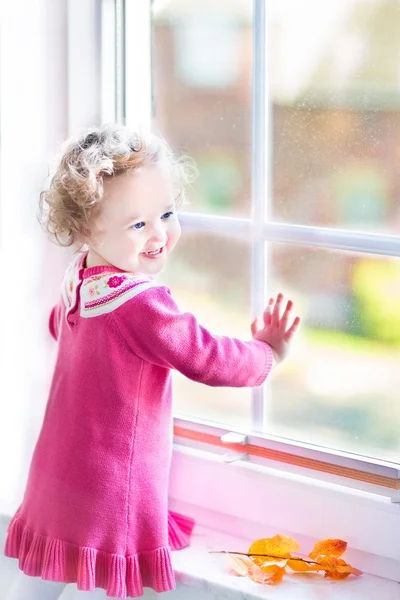 Peuter meisje kijken uit het raam — Stockfoto