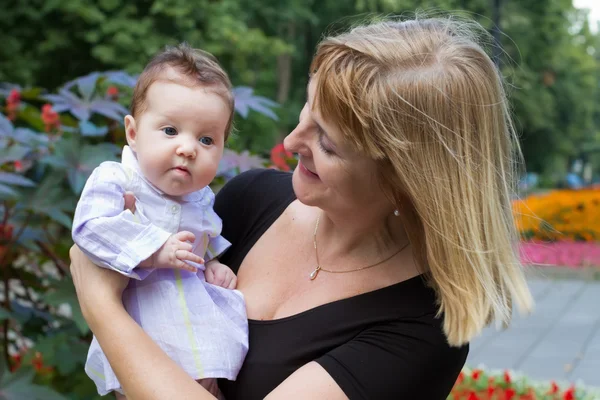 Signora che tiene un bambino in un giardino — Foto Stock