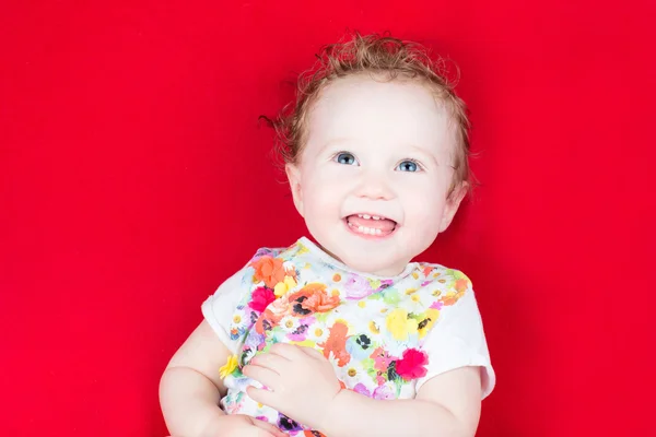 Laughing baby op een rode deken — Stockfoto