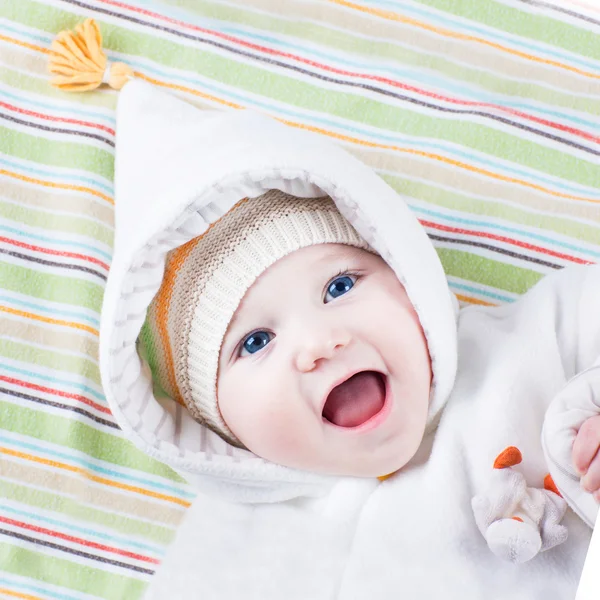 Милая смешная смеющаяся девочка расслабляется на красочном одеяле — стоковое фото