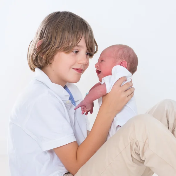 Teenage boy playing with his newborn baby brother — Stock Photo, Image