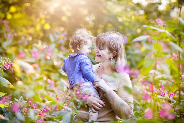 Kobieta z happy baby girl w ogrodzie — Zdjęcie stockowe