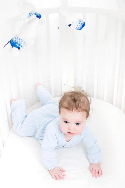 Cute baby playing in a white round crib — Stock Photo, Image