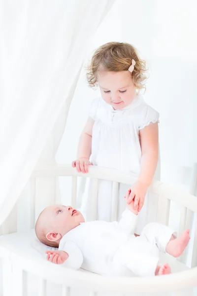 Toddler girl holding hand of her newborn brother — Stock Photo, Image
