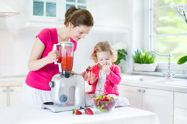 Irl and her young mother making fresh strawberry juice — Stock Photo, Image