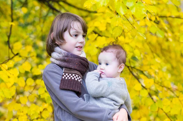 Brother and his baby sister playing in a park — Stock Photo, Image