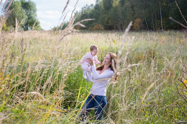 Mother holding a baby girl in a meadow — Stock Photo, Image