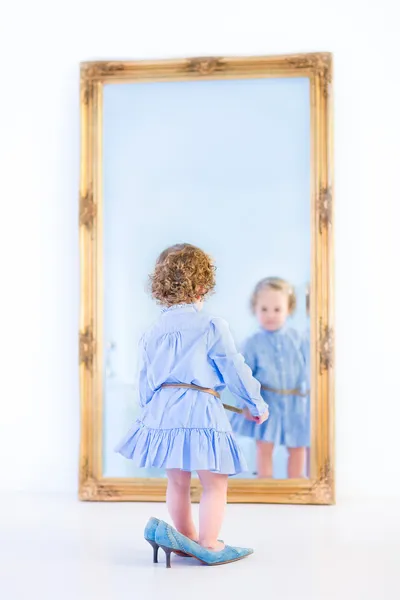 Girl standing in front of a big mirror — Stock Photo, Image