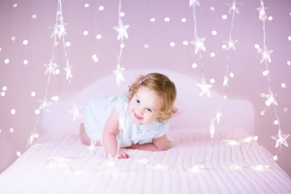 Toddler girl playing on a white bed — Stock Photo, Image