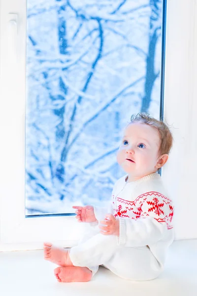 Mooie babymeisje zit naast een venster — Stockfoto