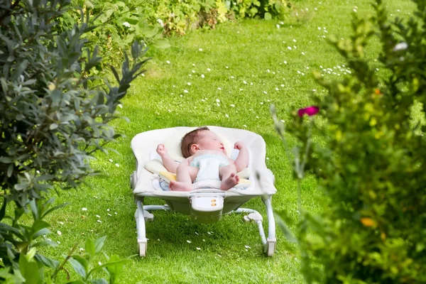 Baby sleeping in a bouncer in the garden — Stock Photo, Image