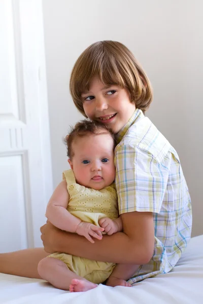 Kleine jongen zijn pasgeboren zus knuffelen — Stockfoto