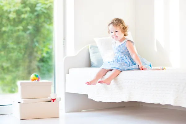 Linda niña sentada en una cama blanca — Foto de Stock