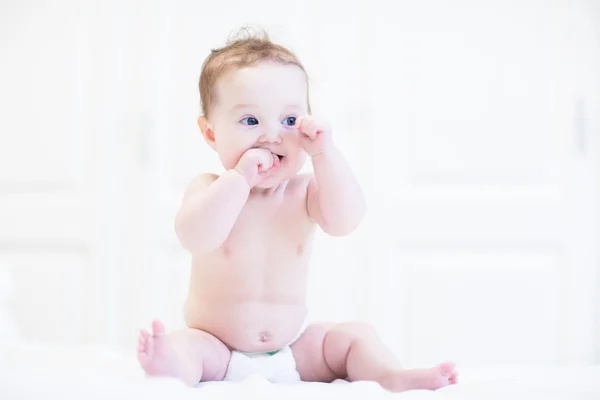 Baby sitzt in einem weißen Kinderzimmer — Stockfoto