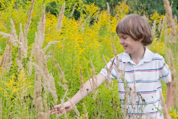 Boy playing in a yellow flower meadow — Stock Photo, Image