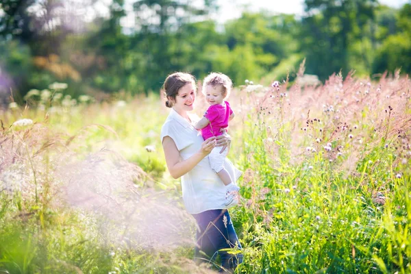 공원에서 그녀의 피곤된 아기 딸을 들고 어머니 — 스톡 사진