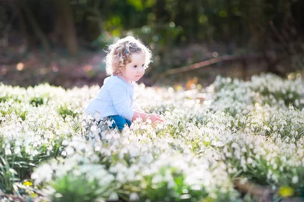 Menina brincando com as primeiras flores da primavera — Fotografia de Stock