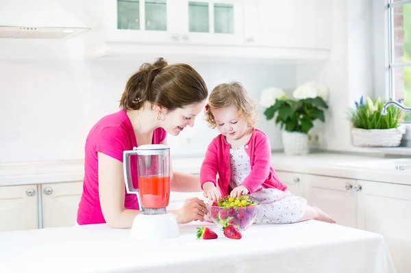 Irl and her young mother making fresh strawberry juice — Stock Photo, Image