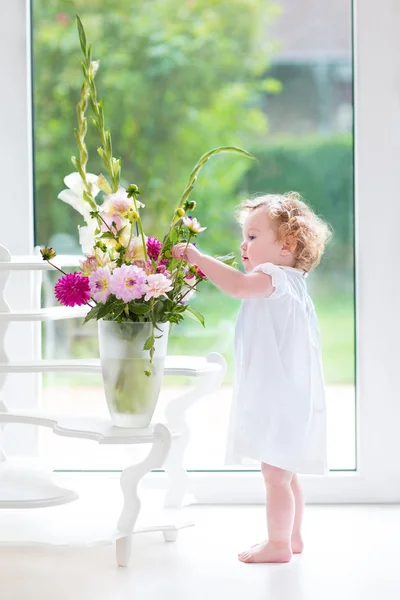 Baby girl smelling beautiful flowers — Stock Photo, Image