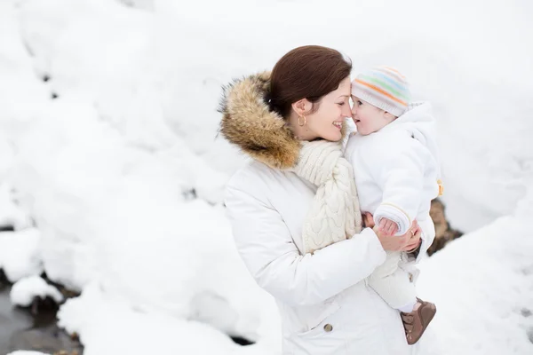 Matka, trzymając dziecko w winter park — Zdjęcie stockowe