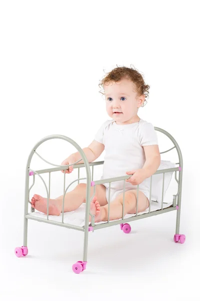 Funny baby girl playing in a doll bed — Stock Photo, Image