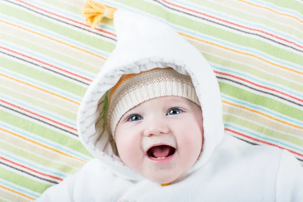 Bonito engraçado rindo bebê menina relaxante em um cobertor colorido — Fotografia de Stock