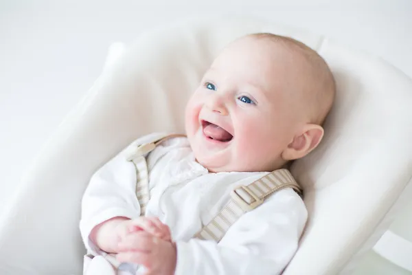 Laughing baby boy sitting in a high chair — Stock Photo, Image