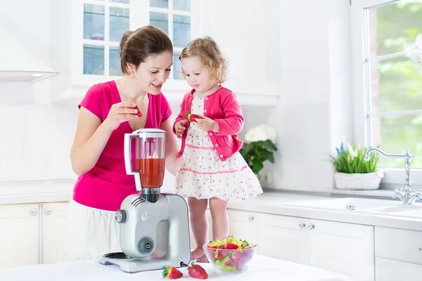 Irl y su joven madre haciendo jugo de fresa fresco —  Fotos de Stock