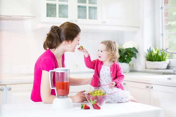 Irl y su joven madre haciendo jugo de fresa fresco — Foto de Stock