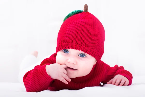 Baby girl in a red apple hat — Stock Photo, Image